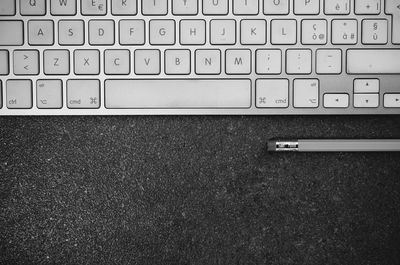 Directly above shot of computer keyboard by pencil on table