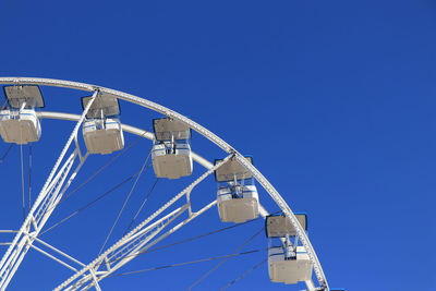 Low angle view of ferris wheel against clear blue sky