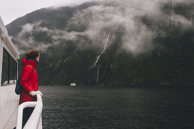 A woman stares up at the surrounding mountains in milford sound, nz