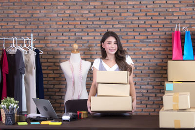 Beautiful asian woman standing among several boxes and checking parcels, working in the house office