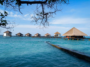 Stilt houses by swimming pool against sky