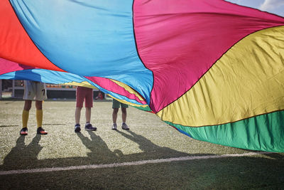 Low section of people by multi colored umbrella