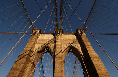 Low angle view of suspension bridge against blue sky