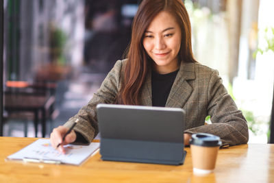 Portrait of young woman using laptop at table