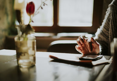 Cropped hand of person using mobile phone on table at home