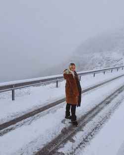 Full length of man standing on snow covered railing