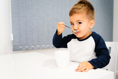 Portrait of boy having drink in cup while sitting at table