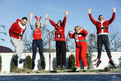 People in santa costumes jumping against clear sky