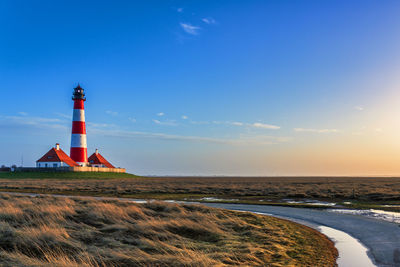 Lighthouse by sea against sky