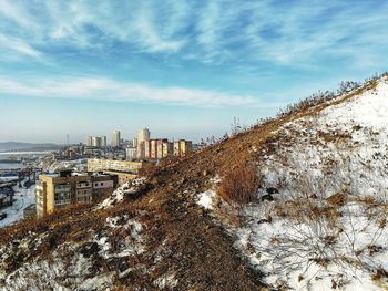 Snow covered trees and buildings against sky