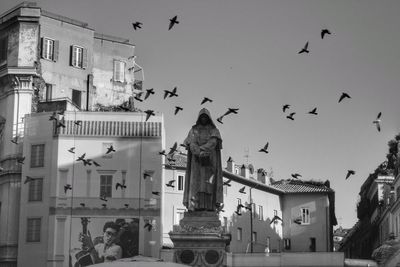 Low angle view of birds flying against buildings in city