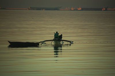 People rowing boat in sea