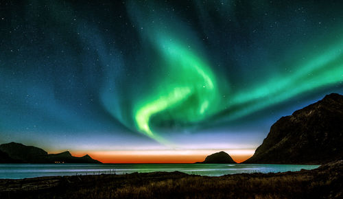 Scenic view of sea and mountains against sky at night