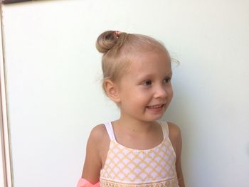 Close-up of girl standing against white wall