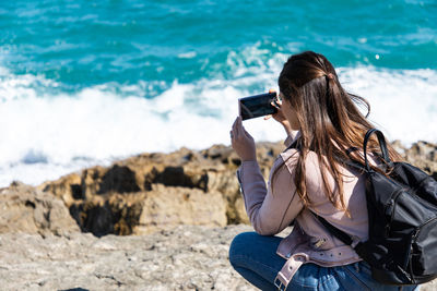 Rear view of woman photographing sea