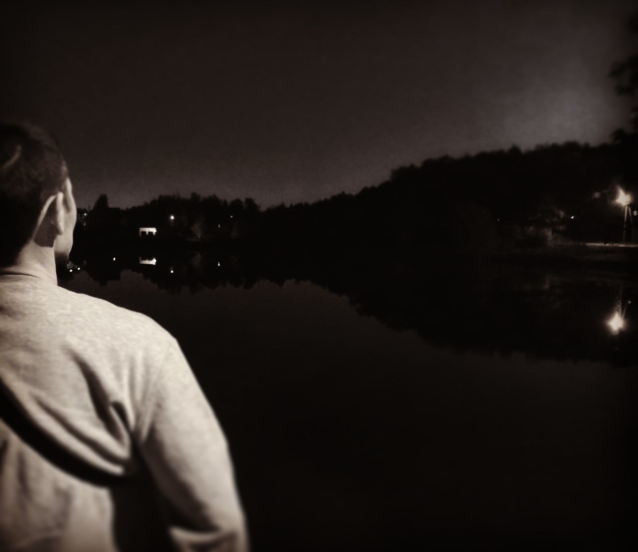 REAR VIEW OF MAN STANDING AT LAKE AGAINST SKY