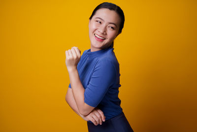 Portrait of smiling young man against yellow background