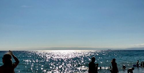 People at beach against clear sky