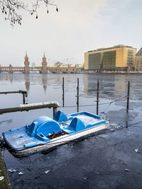 Boats moored on lake in city against sky