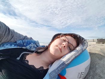 Portrait of beautiful woman lying down against sky