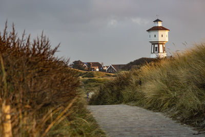 Lighthouse amidst buildings against sky