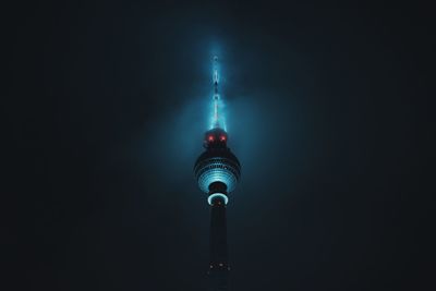 Communications tower in city against sky at night