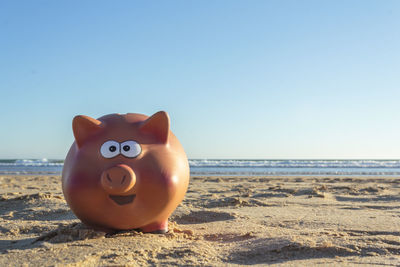 Mailbox on beach by sea against clear sky