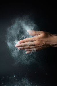 Close-up of woman splashing powder against black background