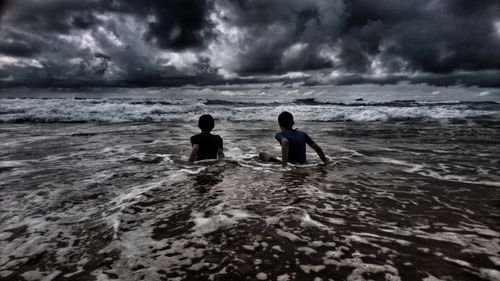People on beach against storm clouds