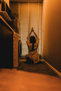 Rear view of woman exercising while sitting at home