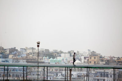 Man standing by cityscape against clear sky