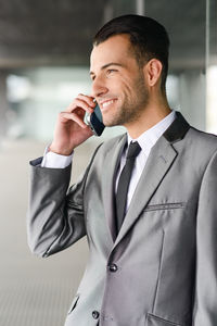 Businessman talking on mobile phone while standing in office