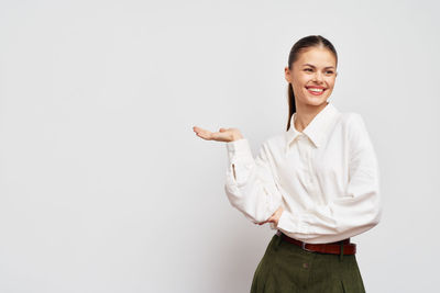 Portrait of young woman standing against white background