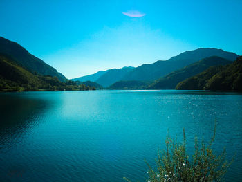 Scenic view of lake and mountains against clear blue sky