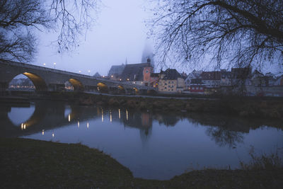 Bridge over river by buildings against sky