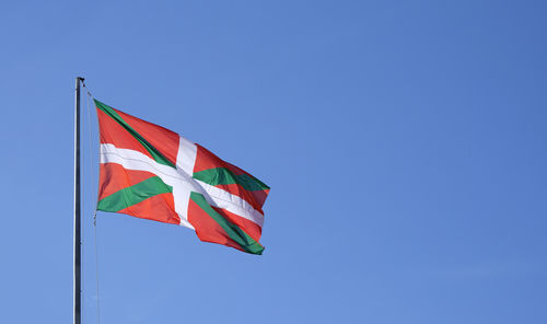 Low angle view of flag against clear blue sky