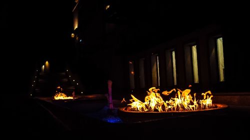 Illuminated candles on wooden structure at night