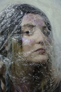 Close-up portrait of woman seen through plastic