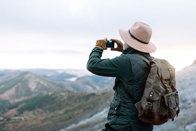 Man photographing on mountain against sky