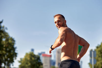 Low angle view of shirtless man standing against sky