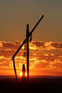 Silhouette cranes against orange sky