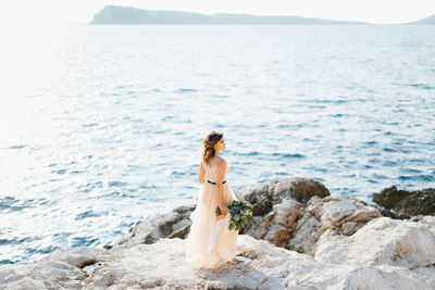 Woman standing on rock by sea