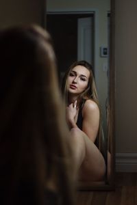 Rear view of young woman reflecting on mirror at home