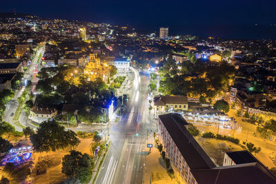 High angle view of illuminated street amidst buildings in city at night