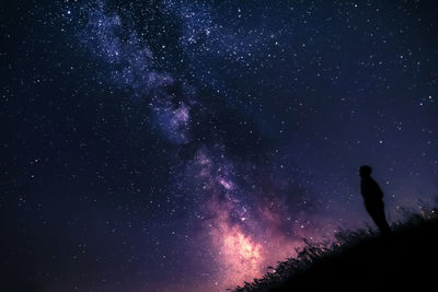 Low angle view of silhouette person on land against sky at night