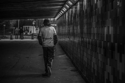 Rear view of man walking on footpath