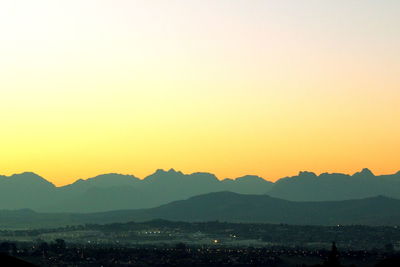 Scenic view of silhouette mountains against clear sky during sunset