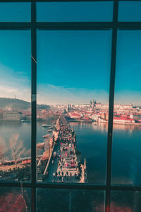 Cityscape by sea against sky seen through window