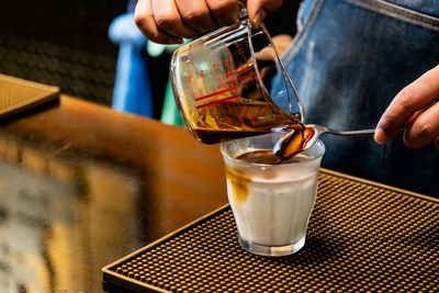 Close-up of hand pouring drink in glass