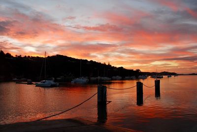 Boats moored at harbor during sunset